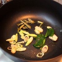 泰式咖喱虾,在炒锅中放入少量的油煸香香茅、南姜、柠檬叶子和咖喱叶。