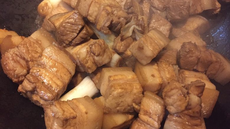 东北乱炖,如图倒入处理好的五花肉,淋入酱油翻炒片刻
