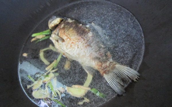 香菇豆腐鲫鱼汤,把鱼移至大点的锅内,加入盖过鱼身的开水,把煎过的姜葱加入