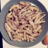 泰式酸辣鸡爪,处理完的鸡爪，放进加了一勺黄酒和姜片的沸水里煮开，大约三五分钟，用筷子戳一下，戳进去了就好了，想吃脆的劲道的就早点出锅，马上放到冷水里冲洗。
事先在冰箱里冰好一盆冷开水，鸡爪洗干净后，放到冰水里激一下。
