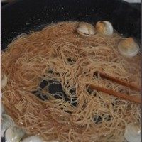 海鲜炒米粉,此时蛤蜊还没张口,倒入米粉,改用筷子不断挑起米粉抖落着翻炒。
