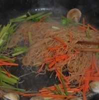 海鲜炒米粉,炒到锅中汤汁基本收尽,倒入蔬菜丝继续翻炒至米粉干爽,蛤蜊开口。