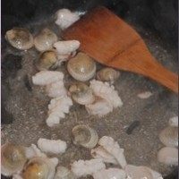 海鲜炒米粉,锅中放油(稍微多一点儿),倒入蛤蜊和鱿鱼一起煸炒,放些料酒。看到鱿鱼发白卷起,把鱿鱼盛出。蛤蜊继续在锅中。
