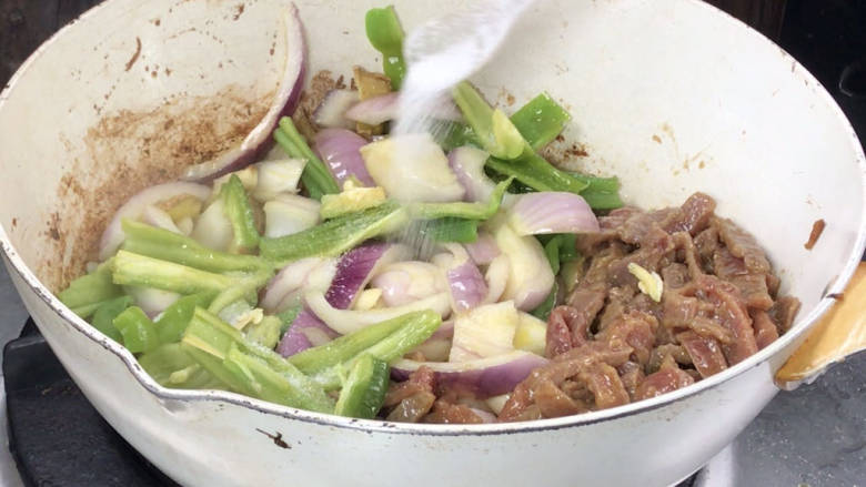 青椒炒牛肉,放入青椒和洋葱炒匀,加盐炒匀至断生