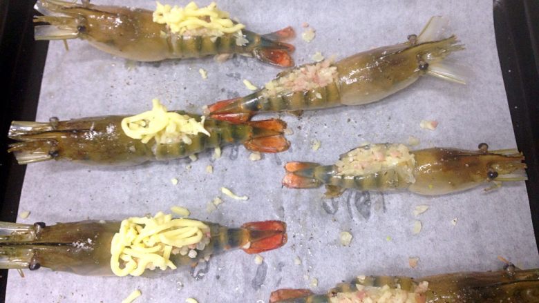 芝士焗大虾,用手指撑开虾背,小勺子把菜料塞进虾背,再铺上芝士碎。