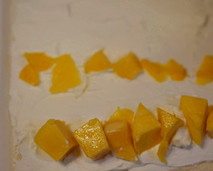 芒果烫面蛋糕卷,出炉连烤盘在台面上从上往下大力震一下,震出热气,然后连同烘焙纸将蛋糕片移在烤架上降温,等待蛋糕体降温的时候重新拿一张新的油纸,盖在蛋糕体上面,以免蛋糕体干掉。