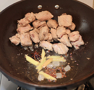 牛肝菌焖排骨,锅里倒入油,先将排骨倒入煸炒,炒至排骨变色后,将排骨移至一旁,倒入配料炒出香味。
