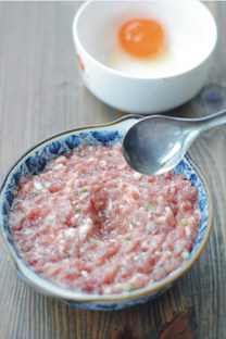 咸蛋黄蒸肉饼,顺时针搅拌均匀。用勺子在肉馅中挖一个小洞,防止蛋黄移位