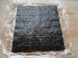 花朵寿司,寿司帘上放保鲜膜,放一片紫菜。