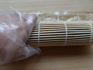 花朵寿司,用卷帘自下而上卷起来,注意边卷边揭掉保鲜膜。