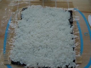 里卷寿司,米饭从左自右,从上至下铺好,盖住海苔。