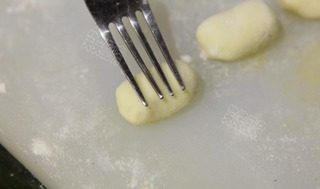 泡菜意大利面疙瘩,用手搓揉光滑,并用食品叉轻压出纹理即成意大利面疙瘩。把做好的面疙瘩放在一个撒有面粉的托盘上,每块之间留出空间,以防止面疙瘩粘在一起。