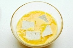 美味的脆皮豆腐,将<a style='color:red;display:inline-block;' href='/shicai/ 9'>鸡蛋</a>在碗里打散，将豆腐放在蛋液里浸泡。