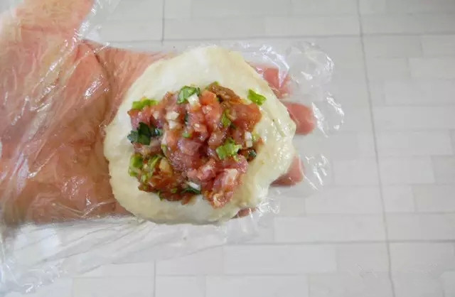 蒙古馅饼,面饧好。手上抹点油,直接用手从盆里拽下一块面,简单团圆拍扁。(也可以倒在面案上用干面粉裹着)放上肉馅,肉馅要尽量多多的放,快速包起包严,收口很容易就粘连上。接着再用手慢慢拍扁,成薄薄的饼坯,依稀可以看见里面的馅。这一系列的动作要快,一气呵成。