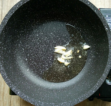 番茄肥牛,锅用大火加热,倒入适量油,加入蒜炒香。