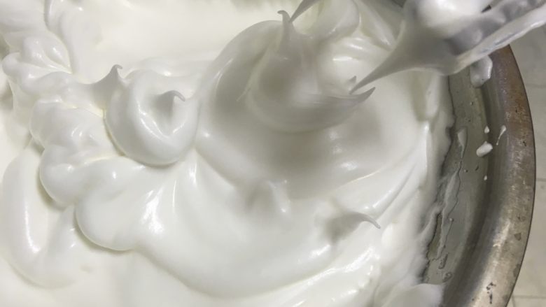 圣诞小雪人奶油纸杯蛋糕,蛋白里加入几滴柠檬汁或白醋,分三次加入白砂糖,将蛋白打发,如图提起打蛋器蛋霜呈直立的小尖儿。