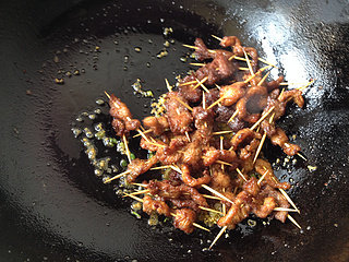 香辣牙签肉,锅中留少许底油,油热后爆香葱姜蒜末,放入炸好的肉串煸炒片刻