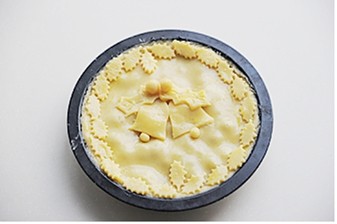 圣诞平安派,再将剩余的派皮擀成3mm左右厚,铺在派馅上,用刮板刮掉多余的派皮,表面刷一层蛋黄液,将多余的派皮刻成叶子状、铃铛等圣诞素材的装饰饼皮,贴在派顶部,烤箱预热200℃,中层烘烤20-25分钟,表面呈棕黄即可出炉,出炉后室温冷却切块享用。