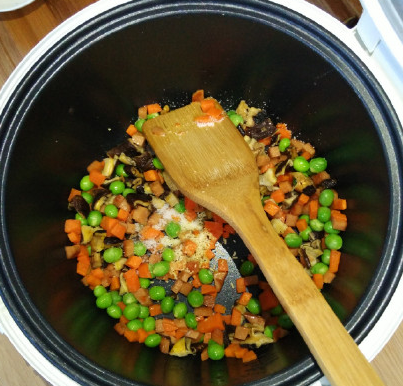 电饭锅什锦焖饭,继续放入胡萝卜、<a style='color:red;display:inline-block;' href='/shicai/ 148'>豌豆</a>铲个半分钟左右,再撒点盐、鸡精拌匀。