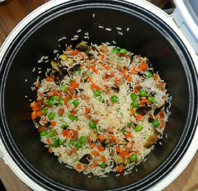 电饭锅什锦焖饭,倒入淘洗后的大米,用铲子把大米和蔬菜拌匀。