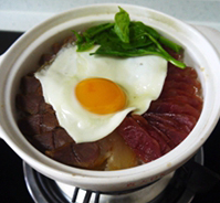 腊味煲仔饭 ,开盖，放上青菜、荷包蛋，浇上煲仔饭调味汁，拌匀即可食用。