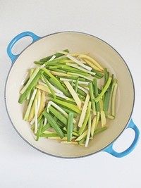 无水版剁椒鱼头,在锅底刷一层油，然后将葱段和姜条铺在锅底。