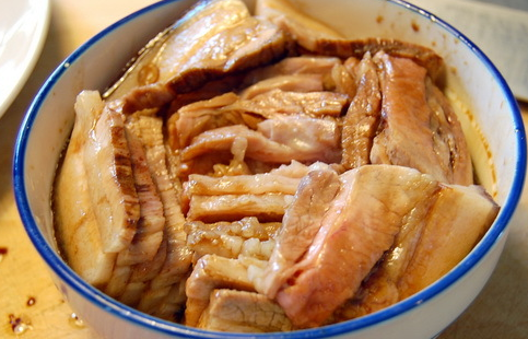 咸烧白,将切好的肉片在料汁中浸一下,肉皮朝下整齐地码在一个大碗内。
