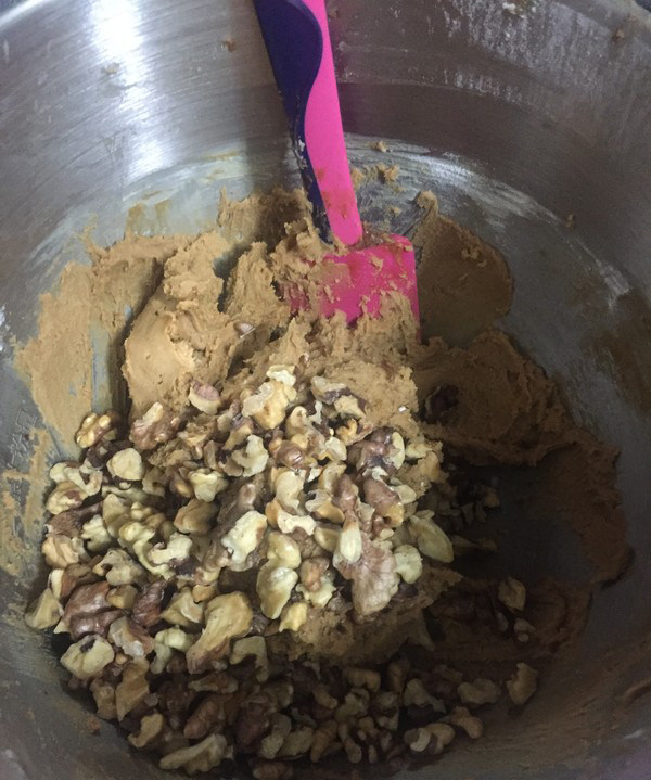 红糖核桃饼干,倒入烤箱的核桃仁,用刮刀搅拌