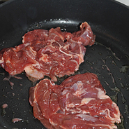 叉烧烤鸭腿,平底锅中倒少量油,烧热放入腌制好的鸭腿肉,两面煎。
