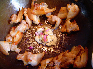 红糟肉,出油后把肉挌至锅边,下蒜粒
