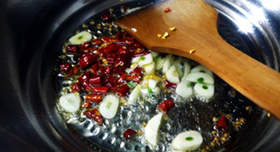 萝卜干炒腊肉,锅中放油,烧热后,下干辣椒圈、蒜末爆出香味