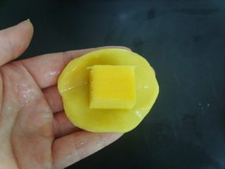 芒果糯米糍,手上粘纯净水,取一小块糯米团压扁,再把芒果放中间包成糯米团。