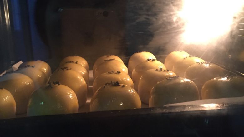 蛋黄酥,如图烤箱180度预热5分钟,期间抹上一层薄薄的蛋液,撒上少许黑芝麻装饰,放在烤箱上下火180度中层25分钟