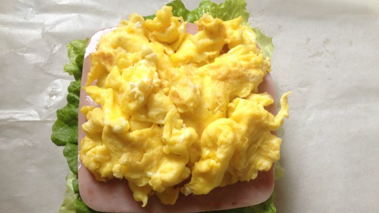 纸袋三明治,铺上2片火腿片,再放上炒鸡蛋;