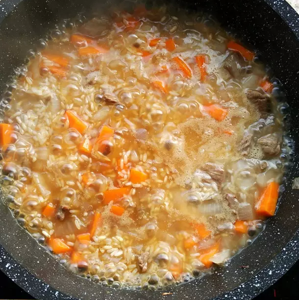抓饭,加入开水,然后倒入大米(糙米)覆盖在食材上面。水量和米量的比例大约是1.5:1,由于大米经过浸泡,吸收了部分水分,最终加入和米量相当的水。用直观法:先加入大米,然后缓缓加入开水,刚好没过大米即可。