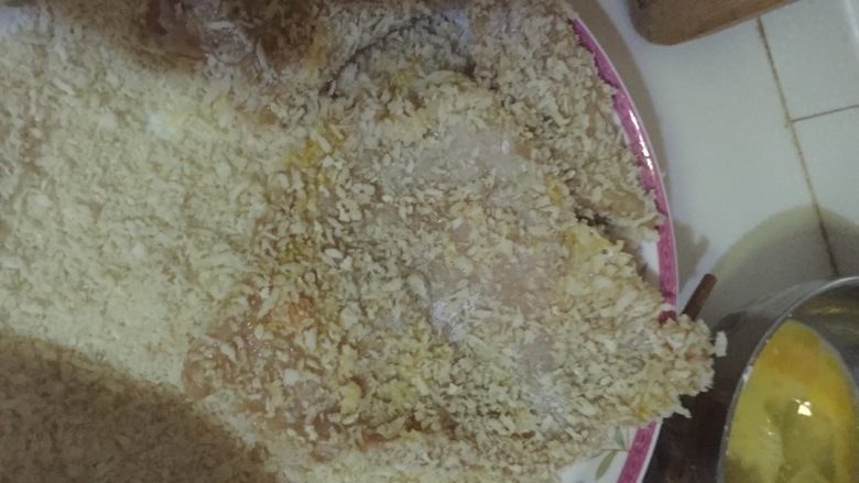 秘制大鸡排,如图第一步先把鸡肉片在淀粉里蘸一下,使鸡肉片被淀粉薄薄地包裹住,第二步,将裹好了淀粉的鸡肉片在蛋液中蘸一下,也是要全部蘸满,第三步:将沾满蛋液的肉片平铺在面包糠上,两手按压使之均匀裹上面包糠