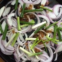 生焗海鲜大杂烩,将洋葱丝、葱段、大蒜铺在铁板上!铺满一层即可!没有铁板的可以用披萨盘,平底锅等等