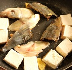 紫苏鱼头豆腐煲,平底锅入少许油,放入腌制过的鱼头,豆腐若是很嫩的可以粘些淀粉再入锅同煎,结实一点点豆腐也可以直接入锅煎,不需要粘淀粉,看买到的是什么豆腐,我个人比较喜欢南风的嫩豆腐,外酥里嫩鲜香烫口的感觉在冬天很美