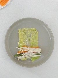 什锦白菜卷,取一片白菜叶,整理呈长方形,将金针菇,芦笋和胡萝卜丝摆在一端。