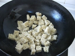 双喜烤麸,锅中倒入油,大火加热至油7成热时,倒入姜丝和烤麸块,煸炒至烤麸的表面变成金黄。