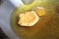 泰式鱼饼,锅中油加热至七八成热后转中火,下鱼丸,用锅铲背面将鱼丸压成饼状。