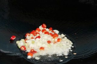 干煸豆角,热锅凉油,放蒜、姜、葱末及辣椒粒炒香