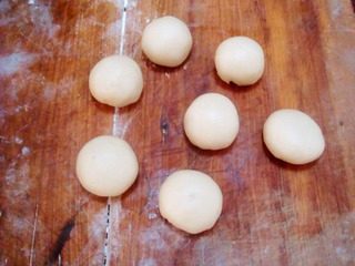 莲花酥,用擀面杖把圆球擀成长方形片,从片的一端卷起成卷,在卷的合缝处再摁扁成片,再从片的左右卷成剂。