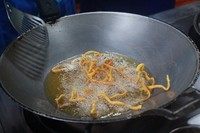 清迈面,拍上面粉的面条入油锅炸至金黄。