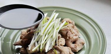 豉油鸡块,锅内倒底油,油开后淋到葱丝和鸡肉上。