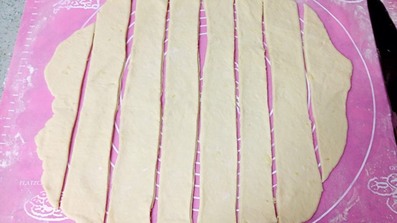 芝士火腿手撕面包,把发酵好的面团取出排气,擀成约3毫米厚的面片,切成约3厘米宽的长条。