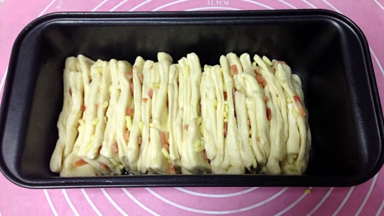 芝士火腿手撕面包,吐司模内壁涂抹一层橄榄油,把小方块竖着逐片码进吐司模,置于温暖湿润环境发酵至满模。