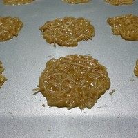椰丝雪花薄脆,取一小勺放在烤盘上,手指沾水将其压扁成直径4公分的圆形。因为烤的时候会膨胀成约8cm大,所以摆放时要留出间距。帖子的量大约可以做16个。