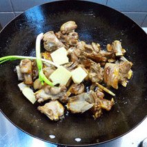 羊肉红烧,当锅中白糖变成红褐色时,下羊肉翻炒,同是加入葱姜。