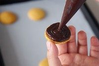 马卡龙,9.烤好后取出冷凉,冷凉好取一个马卡龙把之前准备好的巧克力馅挤在反面